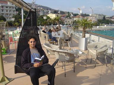 Spencer sitting in a swing chair in a cafe on Opatija's waterfront